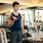 Jeune garçon soulevant des haltères dans une salle de sport