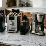 Cinq machines à café différentes alignées sur un comptoir en marbre