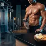 Athlète musclé avec shaker et aliments protéinés au gym